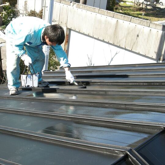 屋根の塗装作業を進める職人