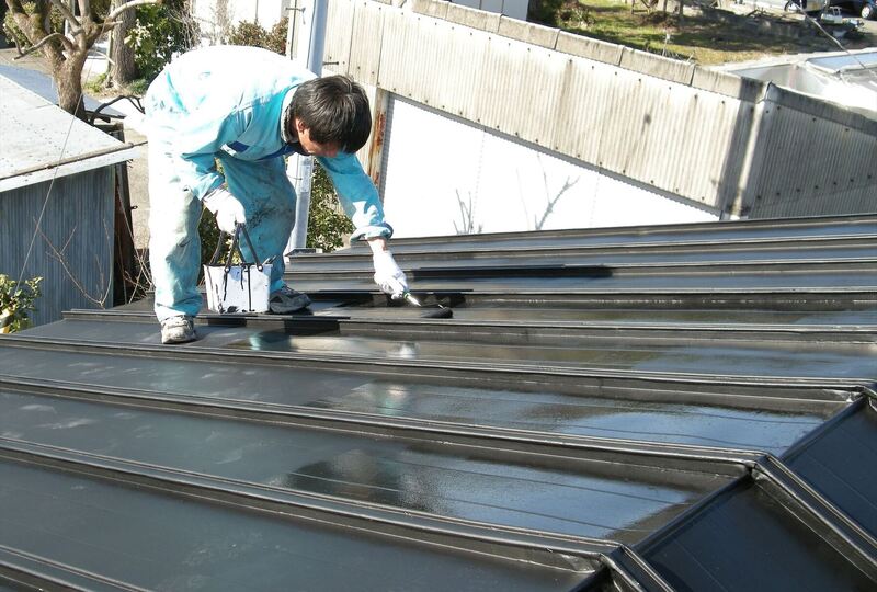 屋根の塗装作業を進める職人